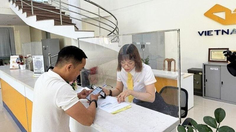 Nhân viên bưu chính hướng dẫn người dân gửi hồ sơ BHXH